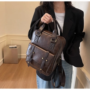 Close-up of dark brown vintage PU leather backpack with gold rivets and buckle detail