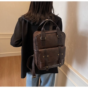 Detail view of the vintage brown faux leather backpack featuring gold hardware and buckles