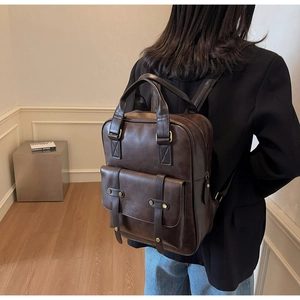 Detail of dark brown vintage backpack featuring metallic rivets and magnetic flap closure