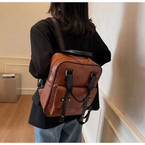 Close-up of vintage brown leather backpack texture and rustic brass button details