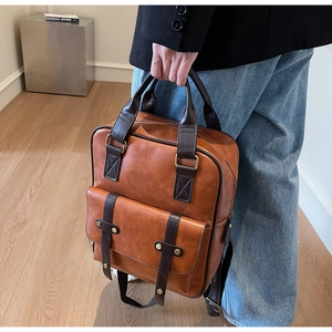 Detailed view of vintage brown leather backpack with golden buckle and textured stitching