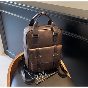 Close-up of vintage dark brown faux leather backpack with metallic rivets on a wooden chair