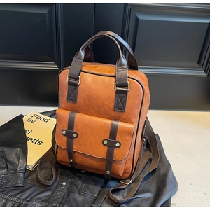 Detail of a brown vintage leather backpack with twin front buckles on a dark background