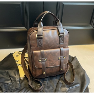 Detailed view of vintage brown leather backpack showing brass buckles and canvas straps
