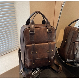 Detailed view of the dark brown vintage backpack with textured leather and brass rivets