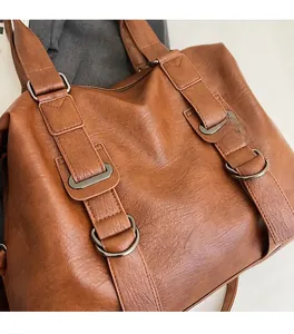 Gros plan du sac cabas en cuir marron montrant la texture souple et les détails métalliques