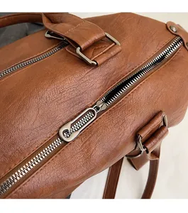 Détail macro de la fermeture éclair argentée et du cuir texturé du sac marron