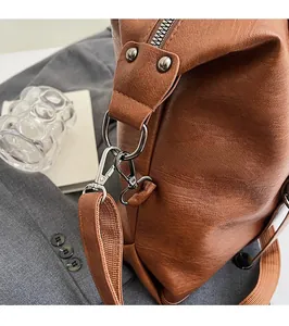 Détail du sac cabas en cuir marron avec crochet métallique et bandoulière tissée