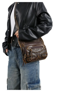 Detailed side view of a brown vintage washed leather crossbody bag with multiple zippers