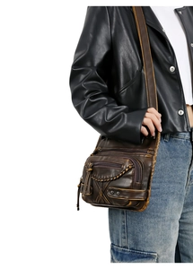 Detail of vintage brown washed leather crossbody bag with woven edges and rivets