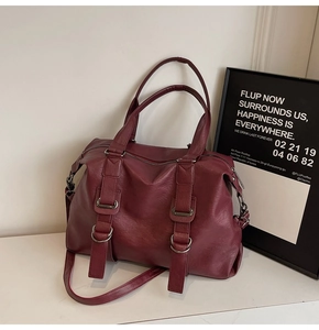 Detail of dark red faux leather tote bag with metallic rings and textured surface