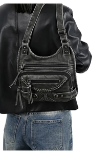 Close-up of vintage black washed PU leather punk shoulder bag with rivets and zippers