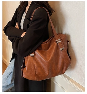 Detailed view of a brown vintage leather tote bag with silver buckle and shoulder strap