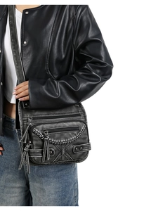 Close-up of vintage black washed PU leather crossbody bag with multiple zip pockets and tassels