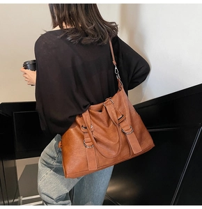Brown leather tote bag featuring metal ring hardware and shoulder strap in lifestyle setting
