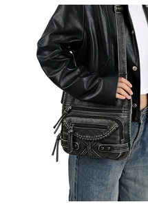 Close-up of vintage washed leather crossbody bag with multiple zippers and rivets