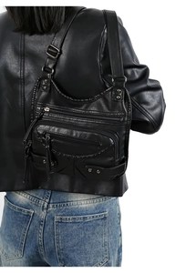 Detail of black washed leather crossbody bag with multiple zippers and studs on model