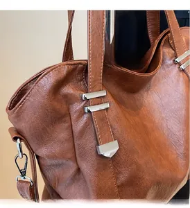 Detail of caramel brown leather tote bag with glossy finish and silver metal hardware