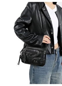 Detail of vintage washed leather crossbody bag with multiple zippers and fringe tassels