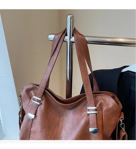 Detail view of durable brown tote bag with leather texture and silver hardware on hanger