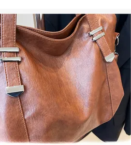 Close-up of brown pebbled leather tote bag detailing soft texture and silver hardware