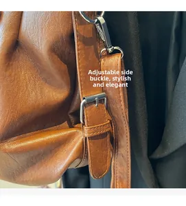 Close-up of adjustable metal buckle and leather strap on a brown tote bag detail