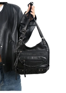 Detail of vintage black washed leather crossbody bag with multiple zippers and studs