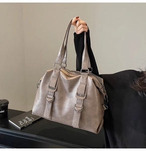 Detail of taupe oil-waxed leather tote bag featuring silver metal hardware and double handles