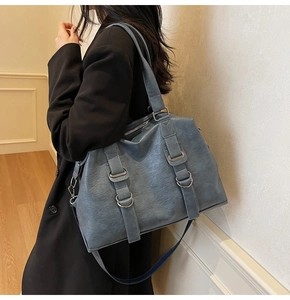 Detail view of large tote bag in blue pebbled leather with silver hardware and shoulder strap