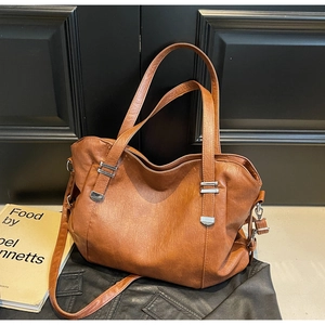 Brown leather tote bag with silver hardware on black jacket and vintage books background