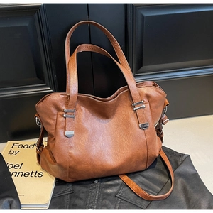 Detail of vintage brown PU leather tote bag with silver hardware and pleated texture