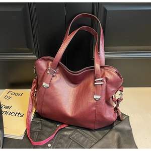 Close-up of wine red faux leather tote bag showing soft grain texture and silver buckles