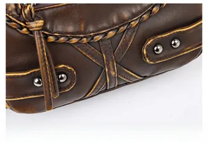 Close-up of vintage brown washed leather bag with woven piping and metal rivets