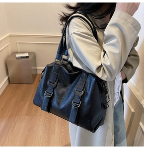 Détail d'un grand sac cabas noir à texture litchi avec boucle métallique ronde