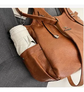 Close-up of vintage brown leather tote side pocket showing a white folding umbrella storage