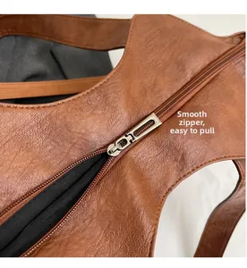 Close-up of smooth gold-tone metal zipper and textured brown leather on tote bag