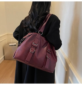 Burgundy faux leather tote bag with silver buckle details shown on shoulder