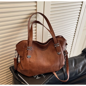 Detail of dark brown tote bag with litchi texture, silver hardware and shoulder strap