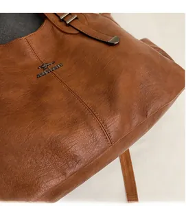 Close-up of brown litchi pattern PU leather texture and kangaroo metal logo detail