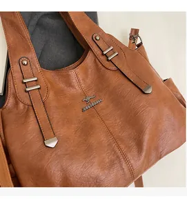Close-up of vintage brown leather tote bag with metal brand logo and lychee texture detail