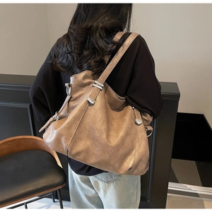 Detailed side view of the brown vintage tote bag with metal buckle and soft faux leather texture