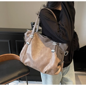 Close-up of vintage brown leather tote bag with silver rivets and textured surface