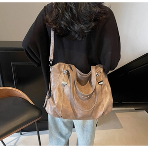Rear view of a model wearing the dark brown pebbled leather tote bag with dual handles