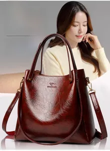 Detail of dark brown leather tote bag with glossy texture and bronze metal hardware
