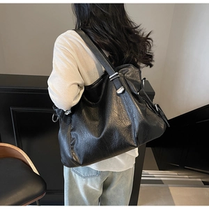 Detailed view of black textured faux leather tote bag with silver adjustable buckle