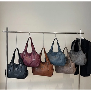 Detailed view of six textured leather tote bags in various colors on a display stand