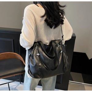 Detail of black faux leather tote bag with oily texture and adjustable shoulder strap