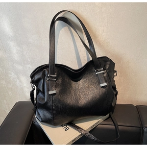 Macro view of textured black faux leather tote bag with silver metal buckles and handles