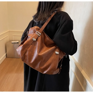 Detail view of large brown retro PU leather tote bag with silver buckle on the shoulder
