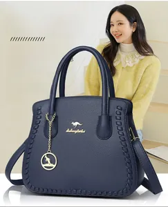Detail view of navy blue lychee grain leather handbag with gold kangaroo logo and charms